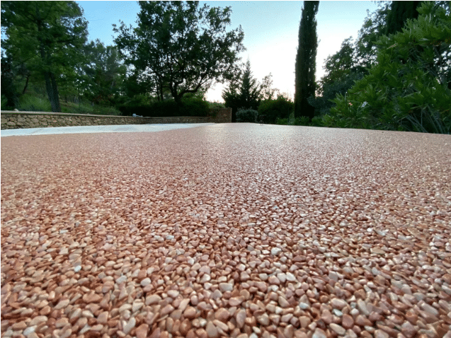 Moquette de pierre en granulats de marbre terracotta pour terrasse extérieure avec arbres en arrière-plan.